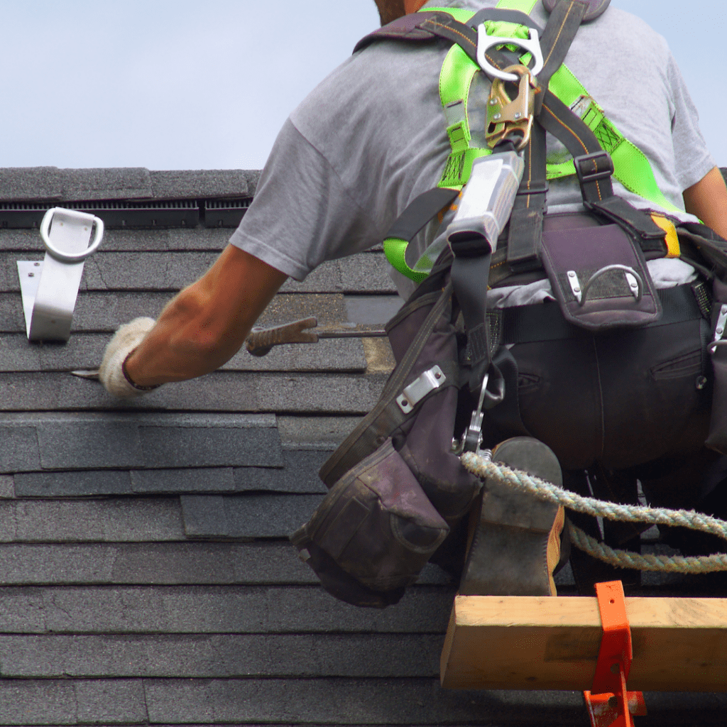 Professionnel des toitures travaillant avec ses équipements de protection sur un toit